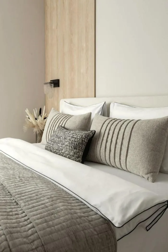 A bed neatly made and styled with cotton bed linen