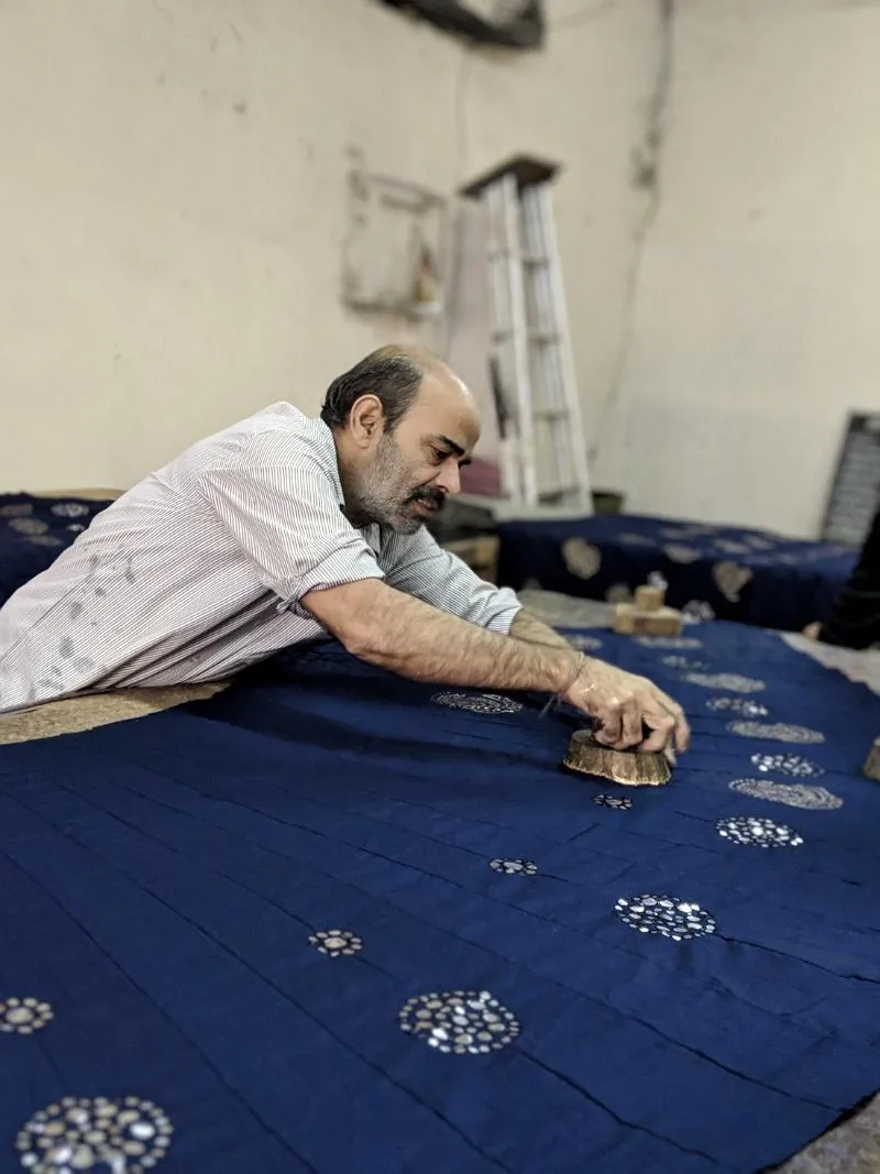 An artisan hand block-printing a length of cloth